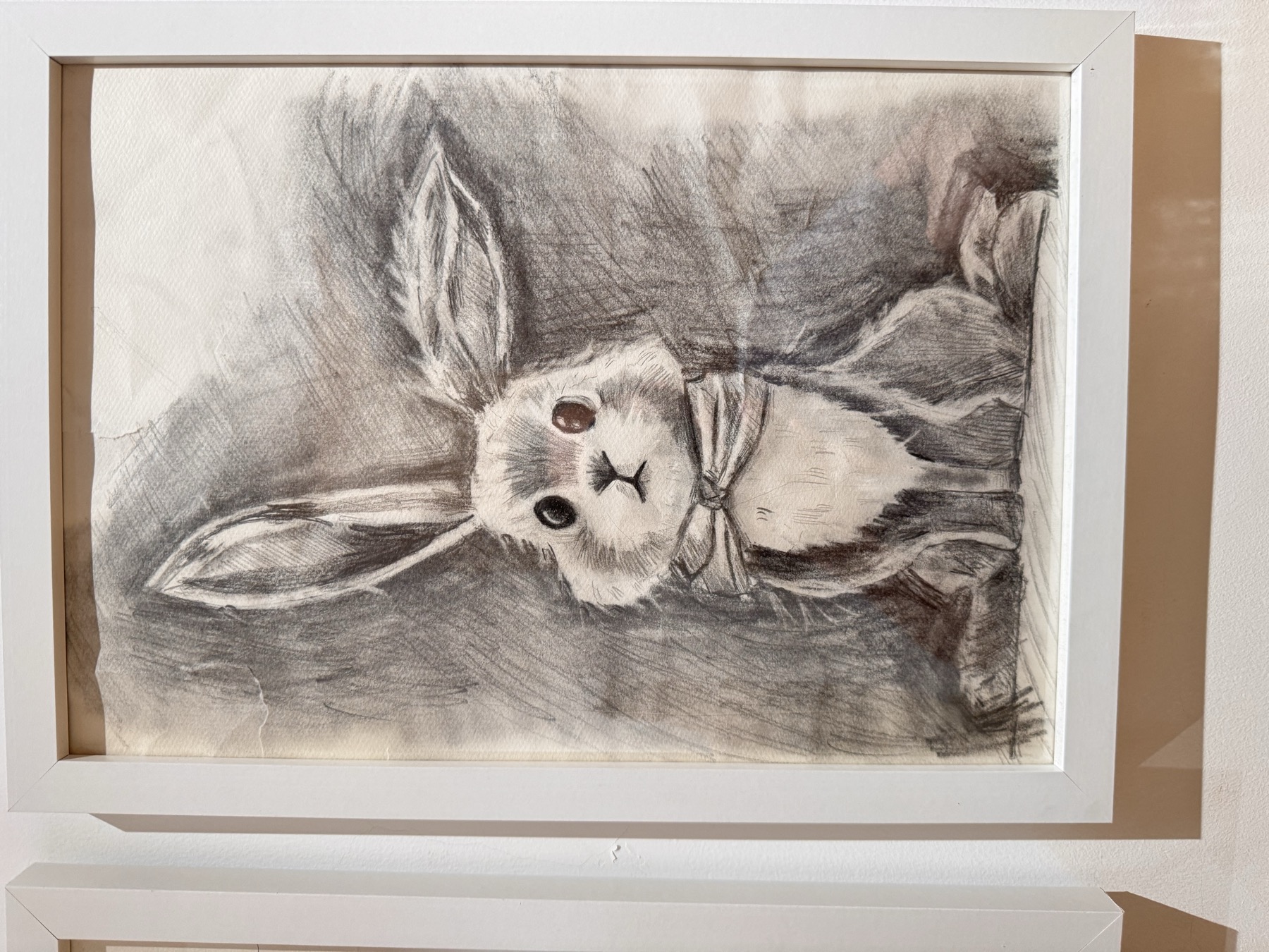 一幅装框的系蝴蝶结长耳兔铅笔素描作品挂在墙面