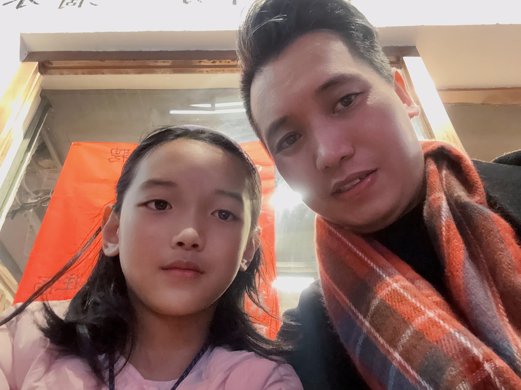 一名女孩与一名成年男性在室内靠近镜头合影