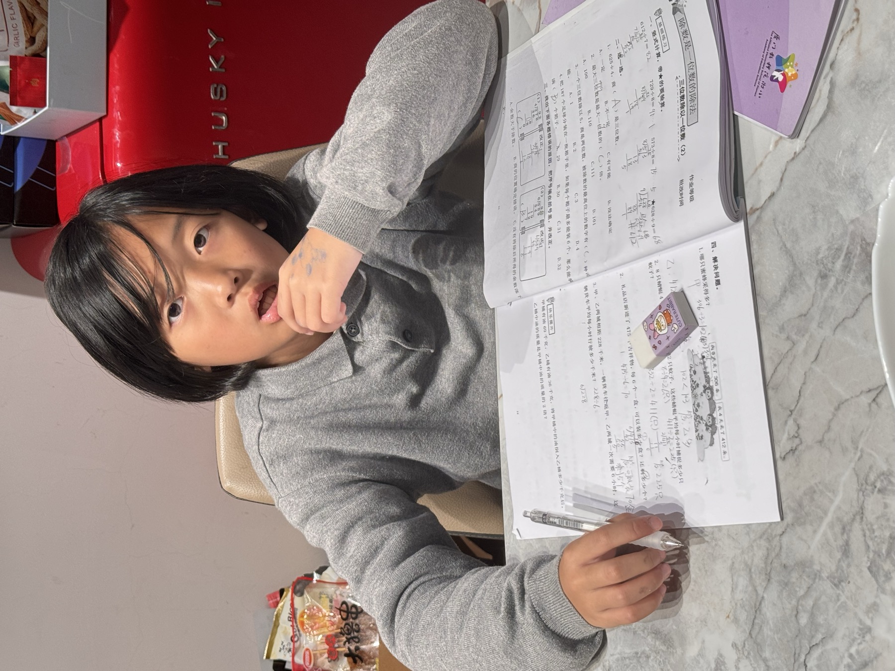 女孩坐在桌边阅读并填写练习册或作文纸