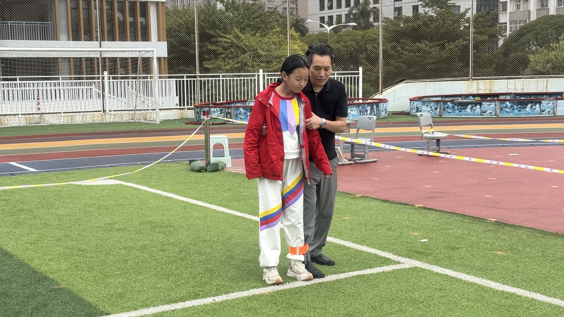 成年男性与女孩在运动场进行两人三足，与旧素材P025完全相同