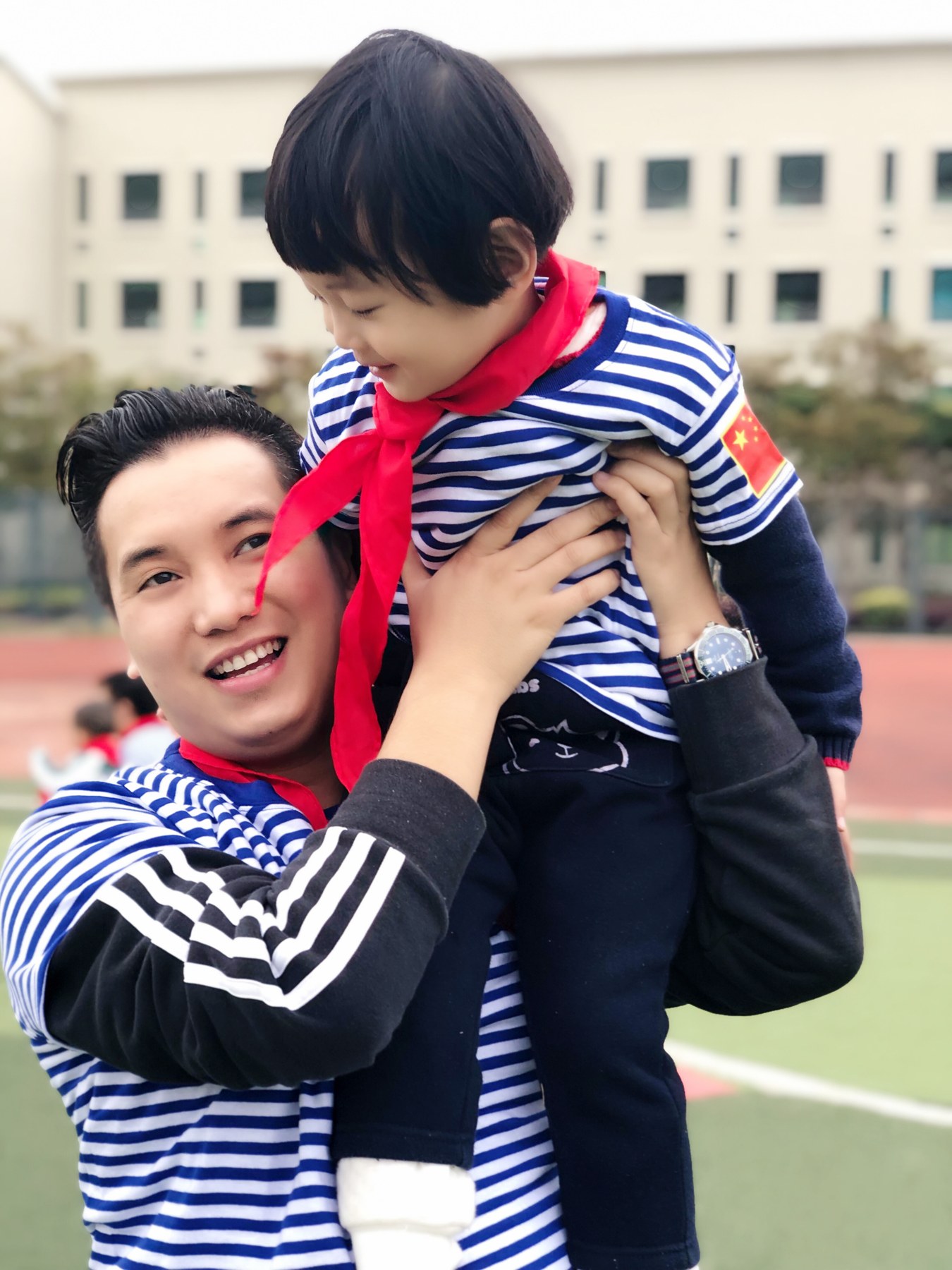 成年男性在运动场抱起幼儿
